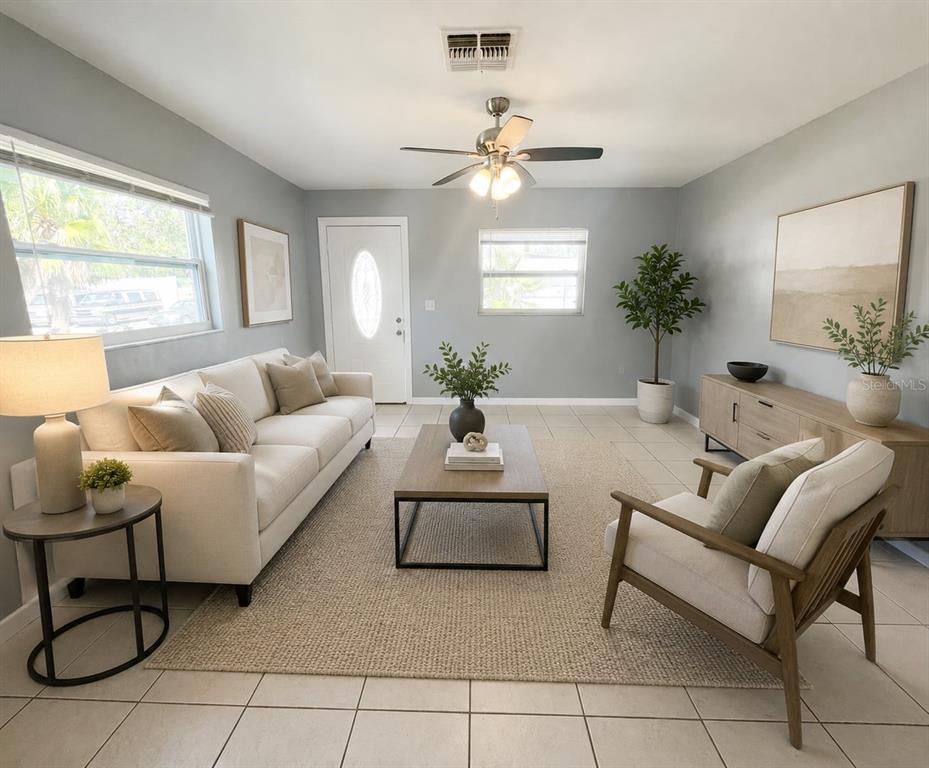 A bright living room features a white sofa, wood coffee table, and light tile flooring — 1551 SWORDBILL DRIVE, HOLIDAY, FL