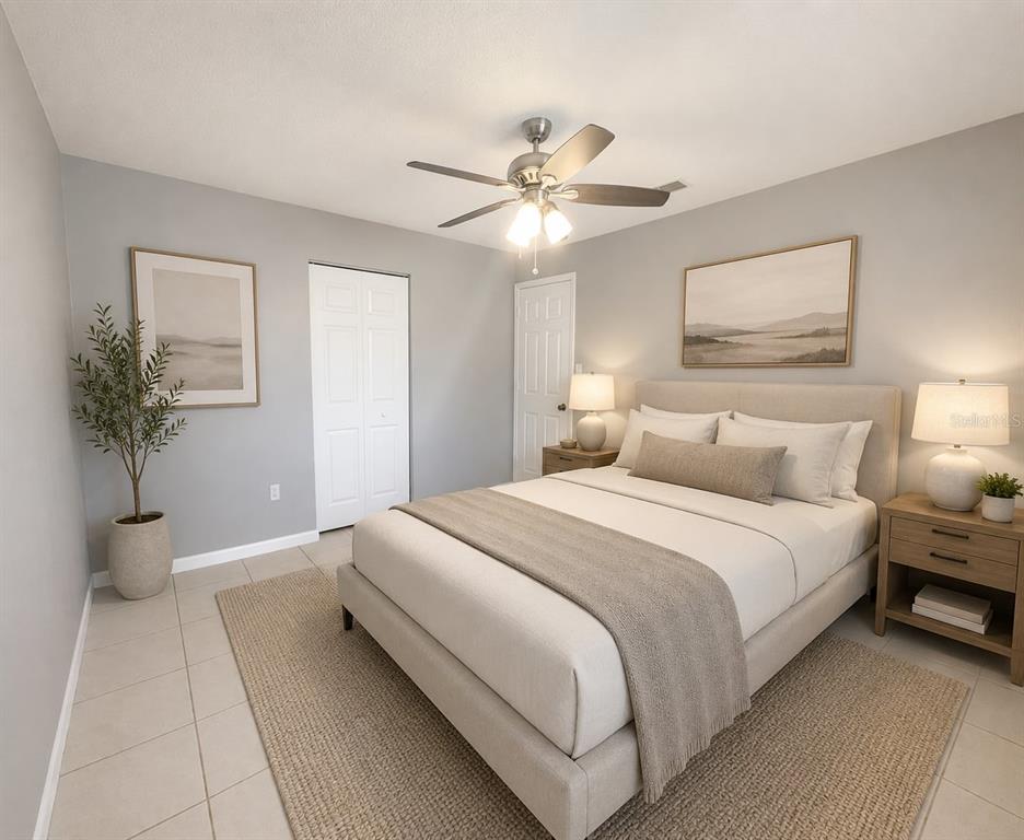A bedroom features a bed with neutral bedding, a ceiling fan, and a large area rug — 1551 SWORDBILL DRIVE, HOLIDAY, FL