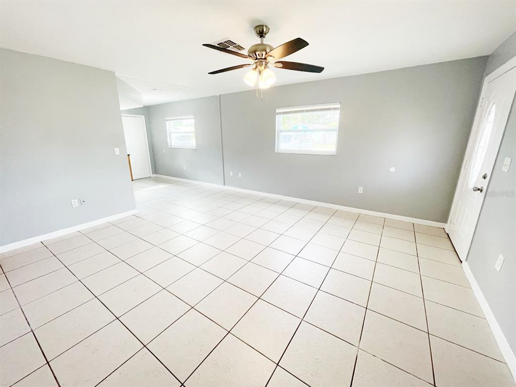 A living room features light gray walls, white tile flooring, and a ceiling fan — 1551 SWORDBILL DRIVE, HOLIDAY, FL
