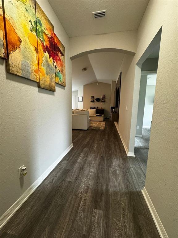 A hallway with wood-look flooring leads toward a living area with an arched entryway — 9028 SE 41ST COURT ROAD, OCALA, FL