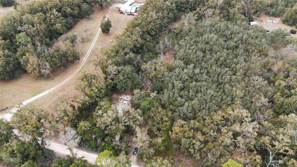 An aerial view shows a wooded lot with a dirt driveway and a nearby house — 911 SW 5TH STREET, TRENTON, FL