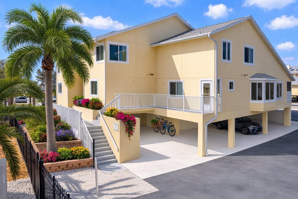 A yellow two-story house with a raised deck, stairs, and covered parking underneath — 109 BAYSHORE ROAD UNIT 10, NOKOMIS, FL