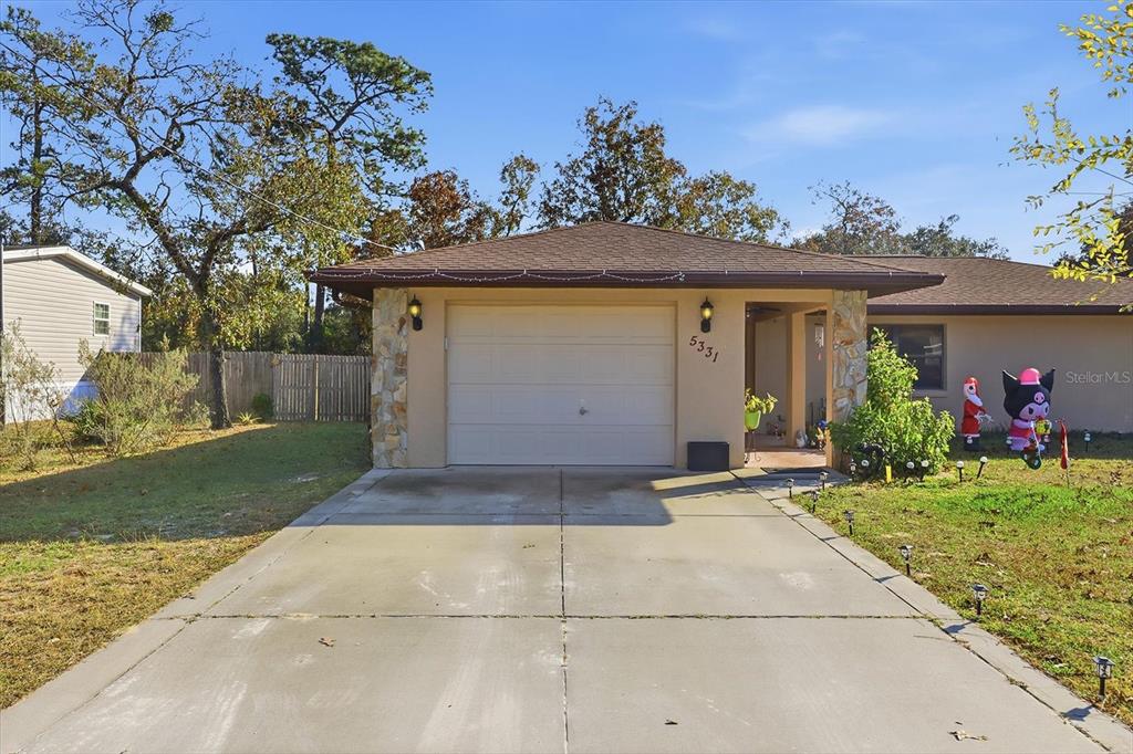 A single-story house features a one-car garage, a concrete driveway, and stone accents — 5331 S HELOISE TERRACE, HOMOSASSA, FL