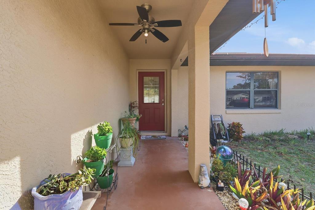 A covered front porch features a red door, a ceiling fan, and potted plants — 5331 S HELOISE TERRACE, HOMOSASSA, FL