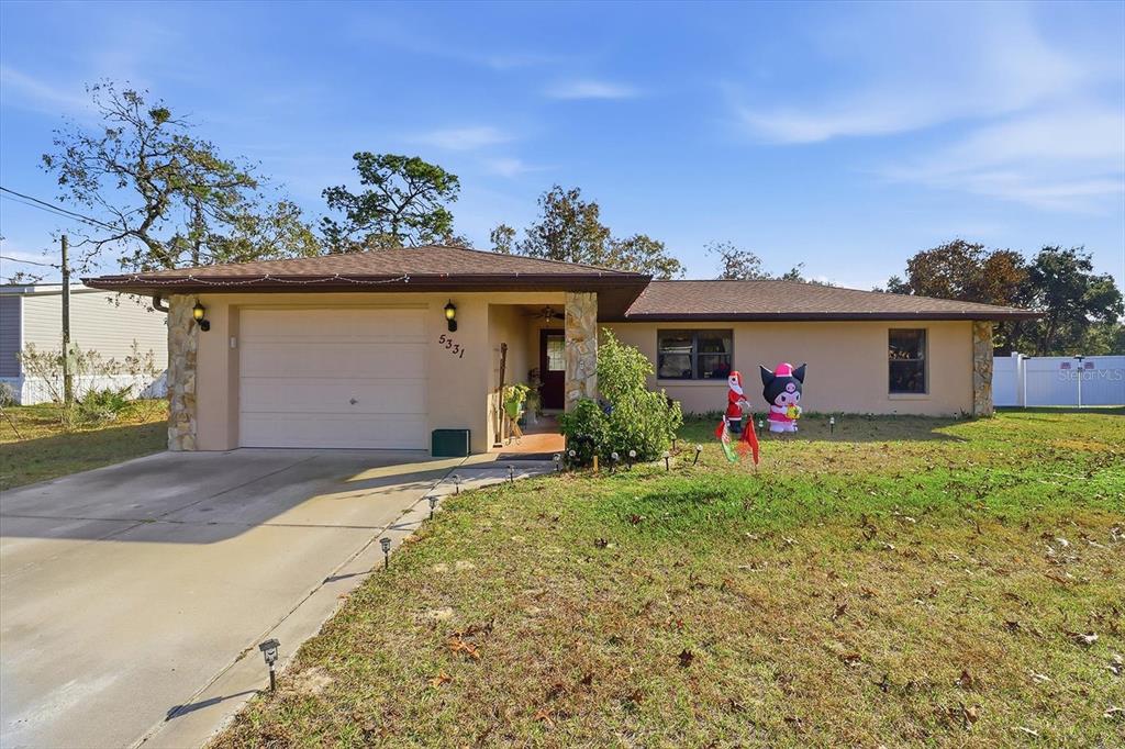 A single-story house with a tan exterior, stone accents, and a front-facing garage — 5331 S HELOISE TERRACE, HOMOSASSA, FL