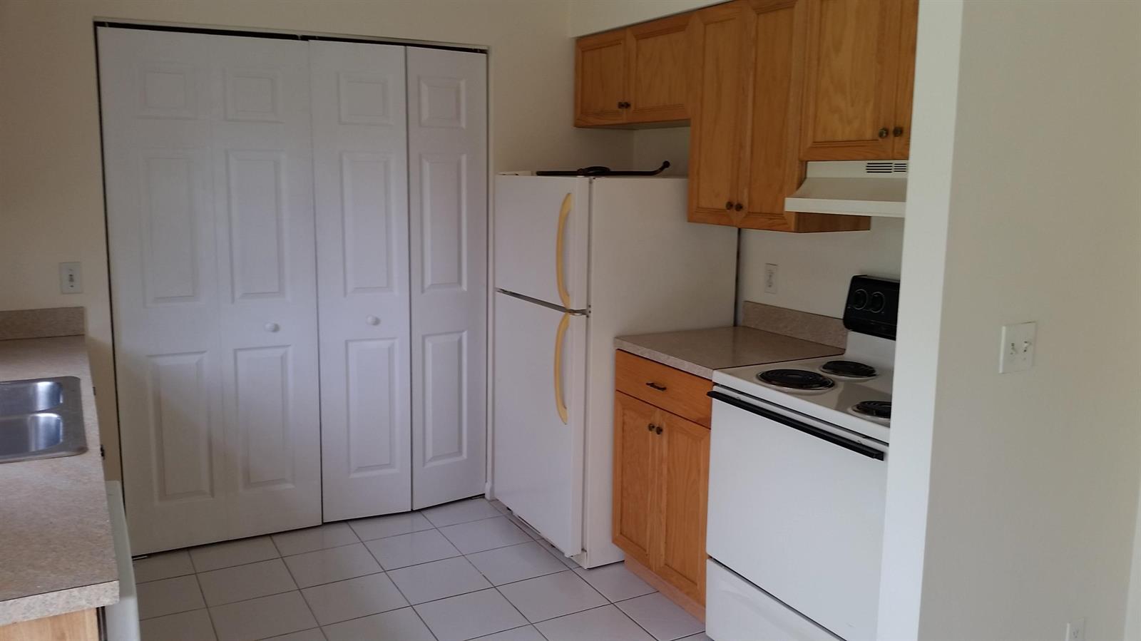 A kitchen features white appliances, light wood cabinets, a laminate countertop, and white tile flooring — 460 Fleming Avenue, FL 33467, FL