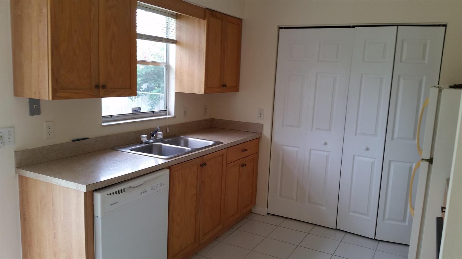 A kitchen features wood cabinets, a double sink, a dishwasher, and white closet doors — 460 Fleming Avenue, FL 33467, FL