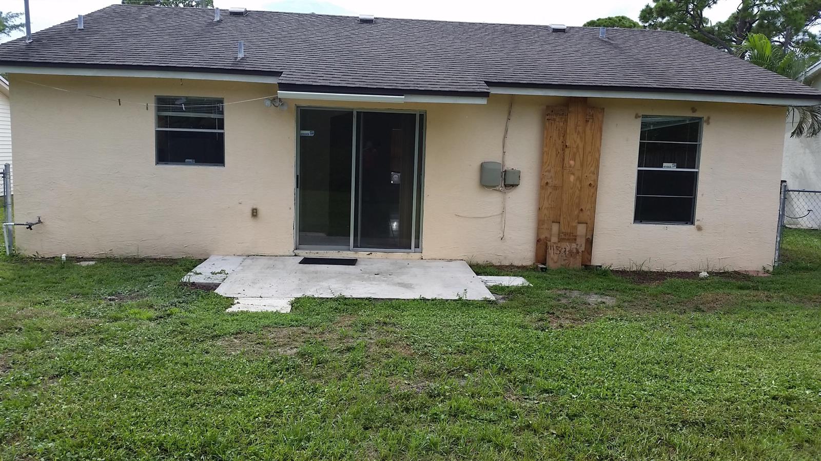 The exterior rear view of a house features a concrete patio, sliding doors, and windows — 460 Fleming Avenue, FL 33467, FL