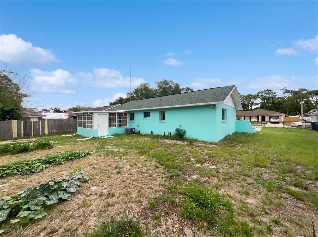 The exterior of a turquoise single-story house features a screened-in porch and a large yard — 4805 BEACON STREET, ORLANDO, FL