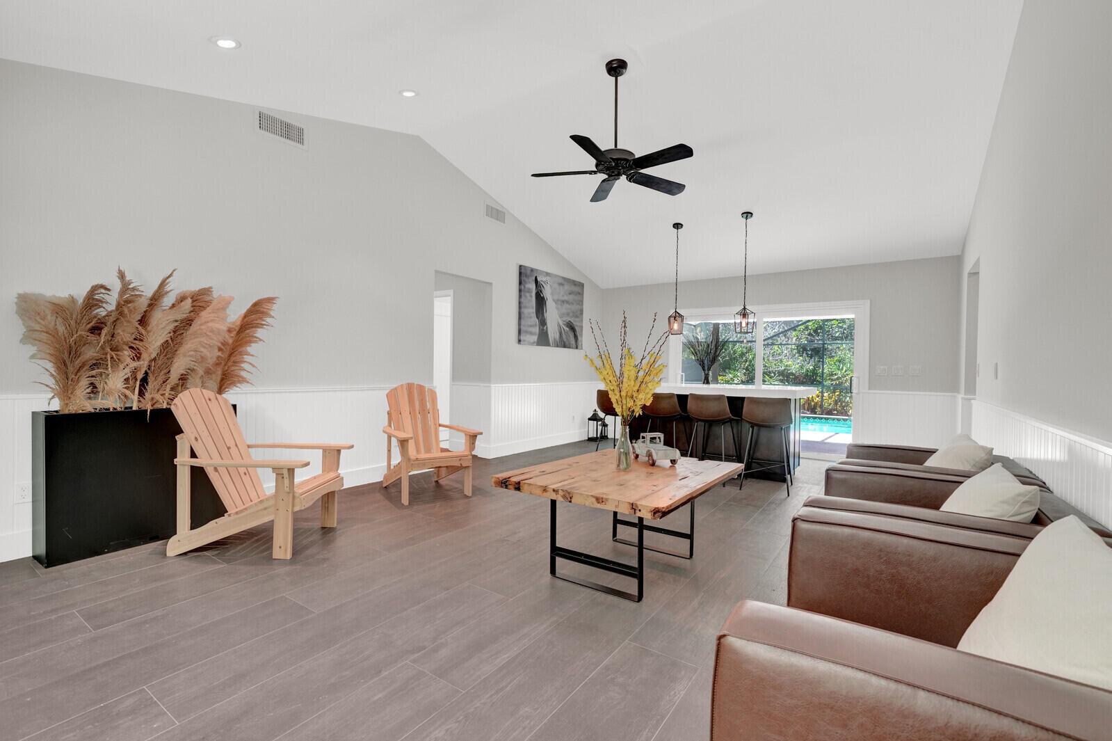 A living room features wood-look tile floors, a vaulted ceiling, and a wooden coffee table — 12216 184th Court N, Jupiter FL 33478, JUPITER, FL