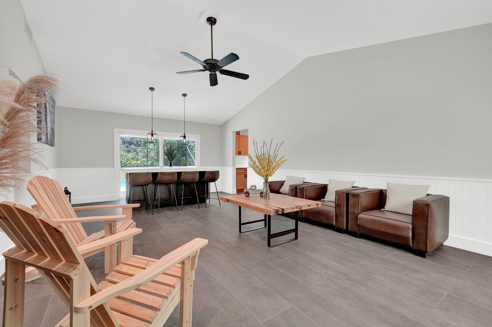 A living room with wood-look tile floors, leather seating, a wooden coffee table, and bar stools — 12216 184th Court N, Jupiter FL 33478, JUPITER, FL