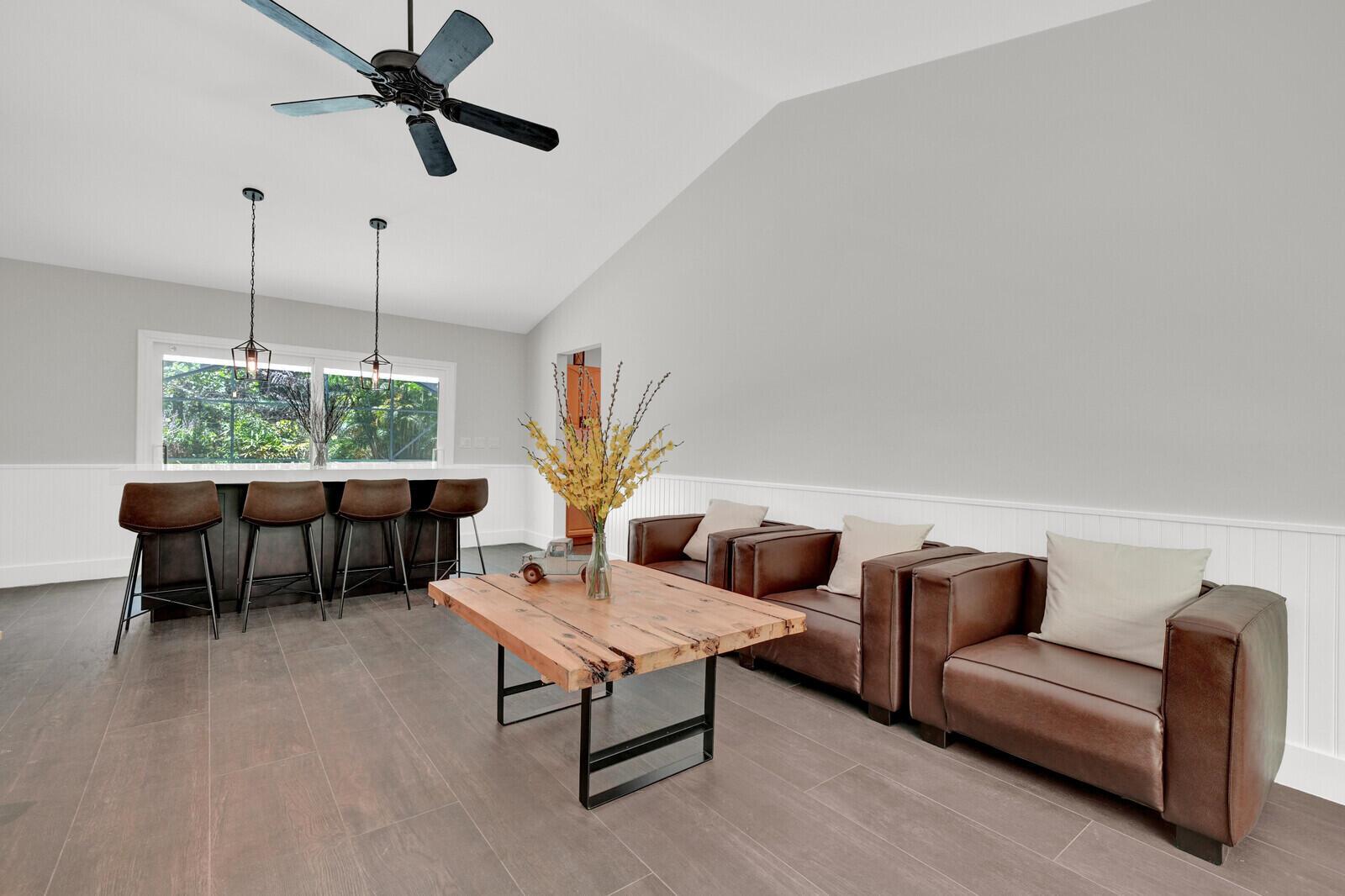 A living room features brown leather chairs, a wood coffee table, and a kitchen bar — 12216 184th Court N, Jupiter FL 33478, JUPITER, FL