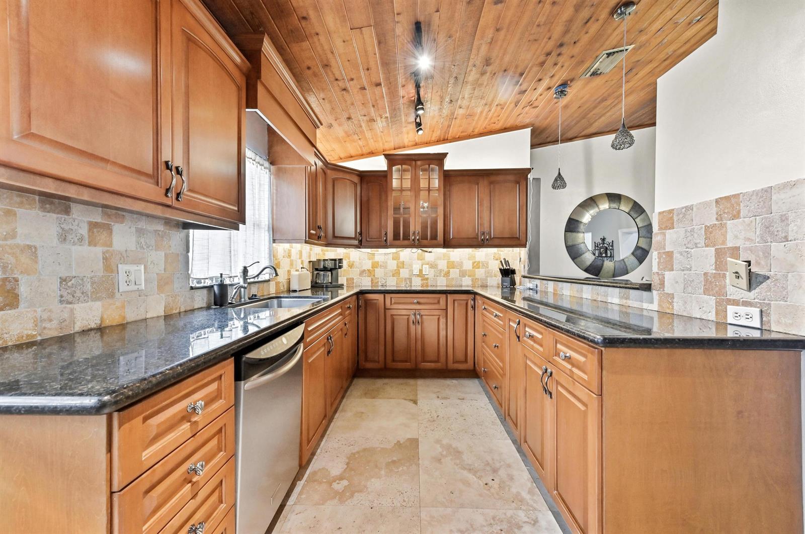 A kitchen features wood cabinets, a vaulted wood-plank ceiling, and stone tile backsplashes — 263 NW 48th Avenue, Deerfield Beach FL 33442, DEERFIELD BEACH, FL
