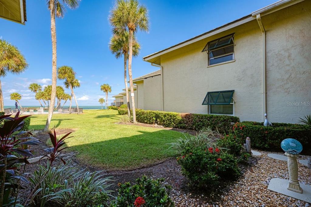 An exterior view of a multi-story building with a lawn, palm trees, and ocean view — 4660 OCEAN BOULEVARD UNIT G1, SARASOTA, FL