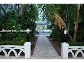 A stone walkway leads toward a building entrance framed by white railings and palm trees — 215 30th St # 22, Miami Beach FL 33140, MIAMI BEACH, FL