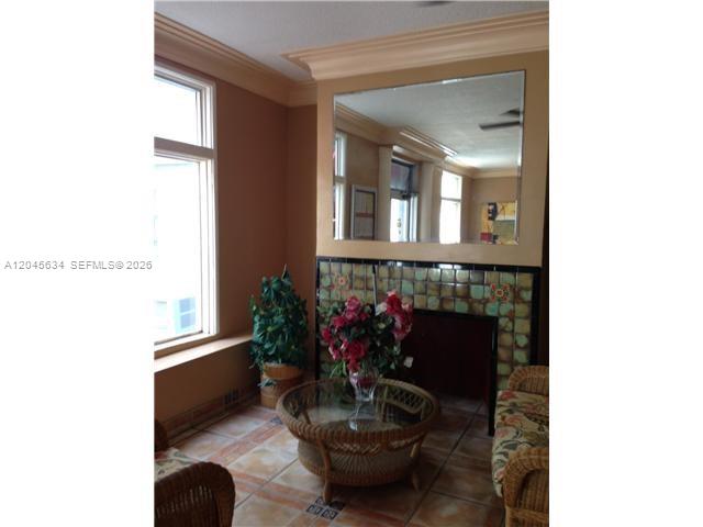 A sunroom features a tiled fireplace, a large wall mirror, and wicker furniture — 215 30th St # 22, Miami Beach FL 33140, MIAMI BEACH, FL