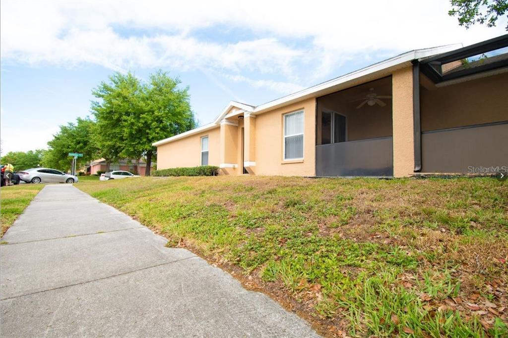 A tan single-story house with a screened-in porch sits next to a concrete sidewalk — 108 SUNDOWN COURT, DAVENPORT, FL