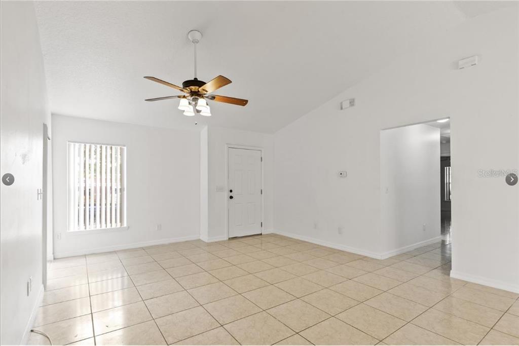 An empty room with white walls, tile flooring, a ceiling fan, and a front door — 108 SUNDOWN COURT, DAVENPORT, FL
