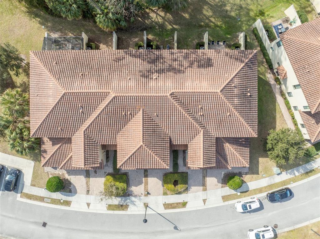 An aerial view shows the tiled roof of a multi-unit residential building and surrounding landscaping — 8177 ROSEVILLE BOULEVARD, DAVENPORT, FL