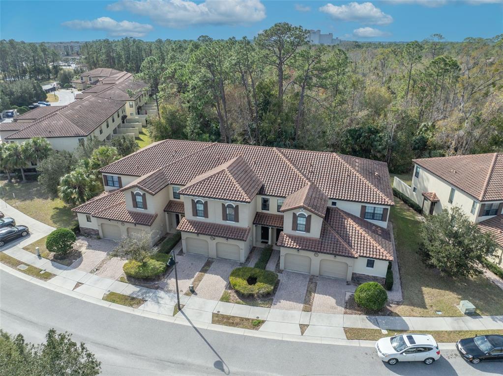 An aerial view shows a multi-unit residential building with a tiled roof and attached garages — 8177 ROSEVILLE BOULEVARD, DAVENPORT, FL