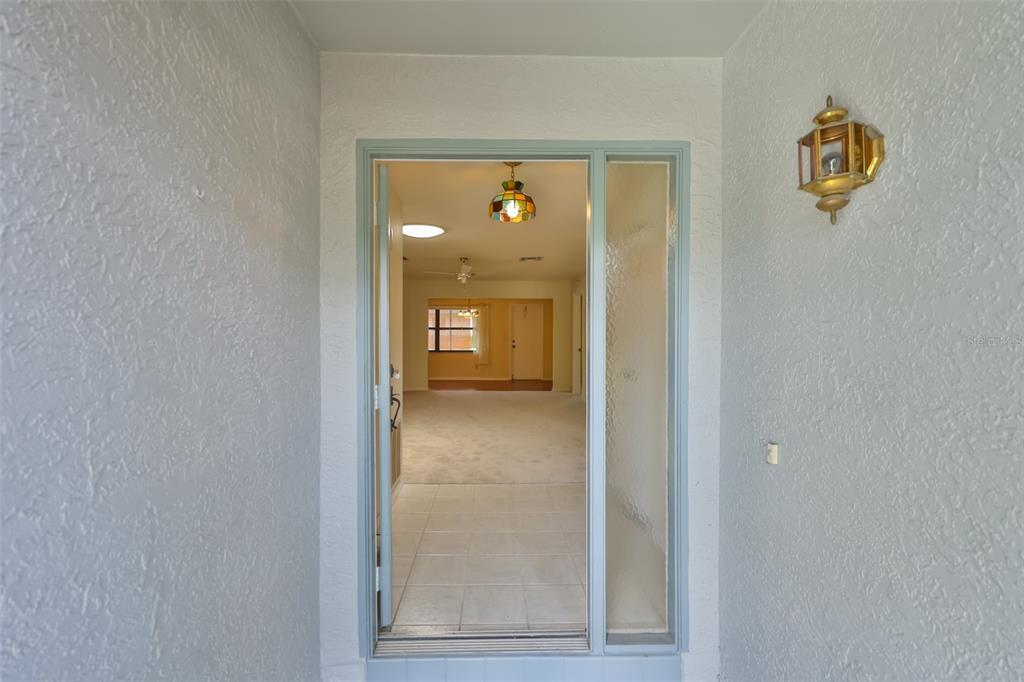 A view through an open front door into a tiled entryway and carpeted living area — 1616 LAYTON COURT, SUN CITY CENTER, FL