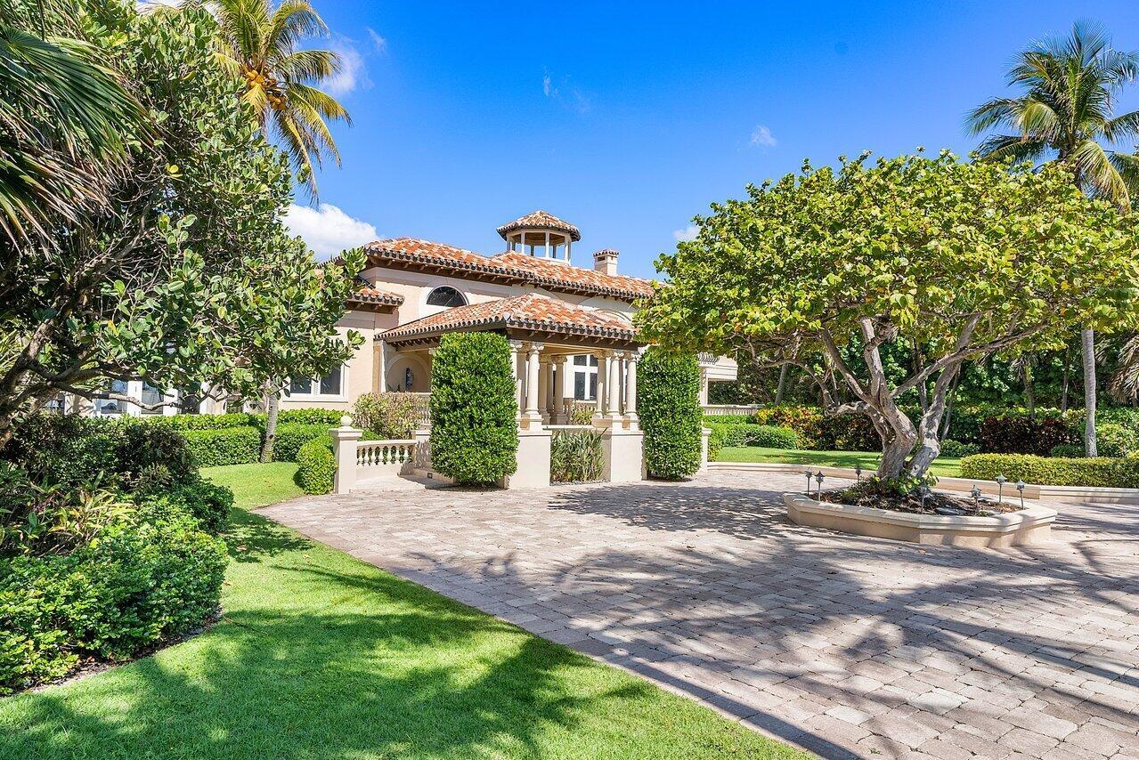 A paved driveway leads to the entrance of a Mediterranean-style home with lush landscaping — 1880 S Ocean Boulevard, Manalapan FL 33462, MANALAPAN, FL