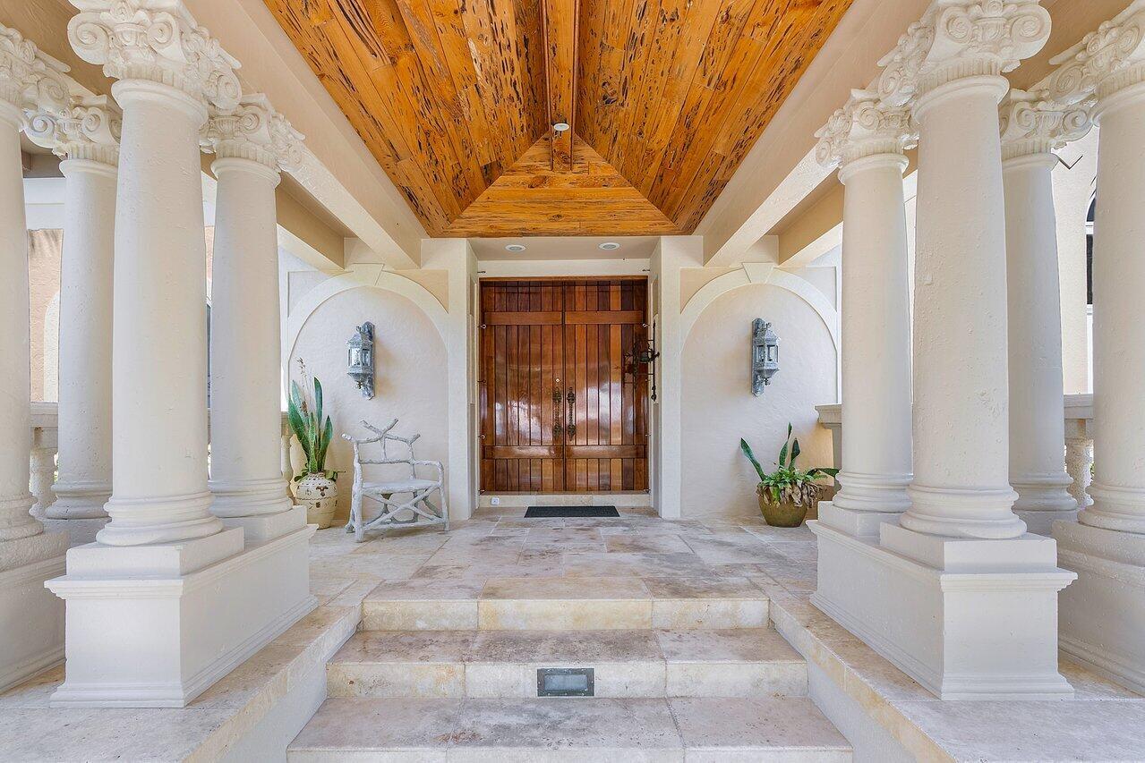 A covered entryway features stone steps, white columns with ornate capitals, and a wood-paneled ceiling — 1880 S Ocean Boulevard, Manalapan FL 33462, MANALAPAN, FL