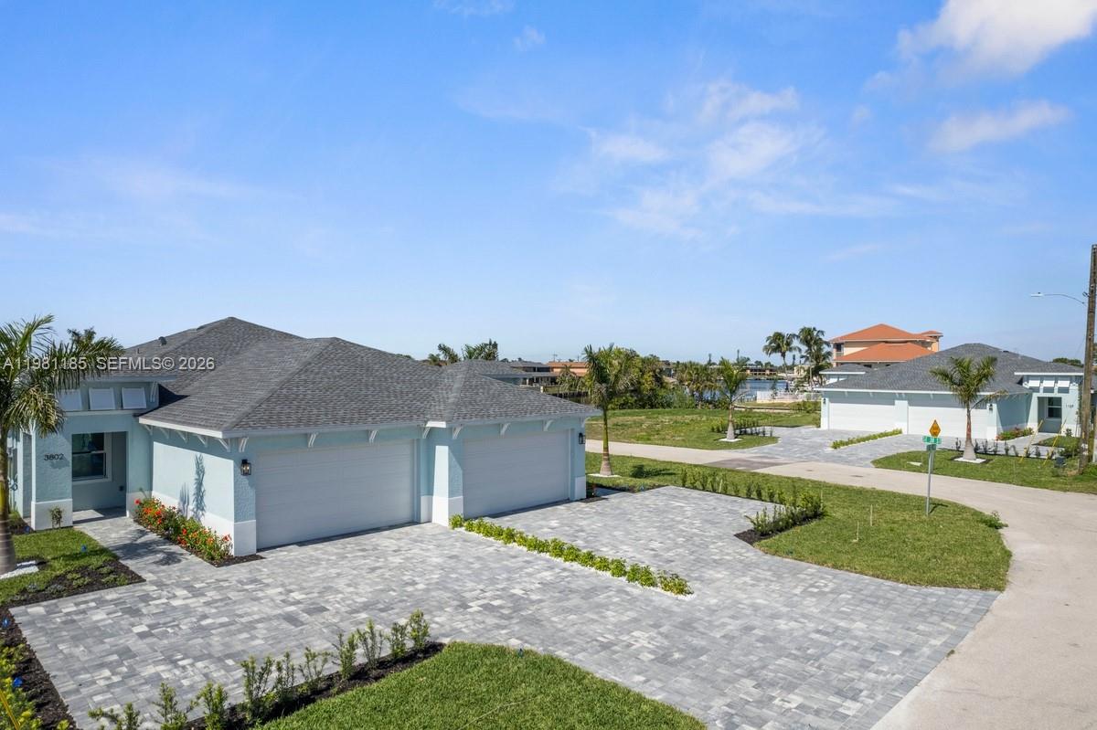 An exterior view of a light blue house with a paved driveway and gray roof — 1107 SE 38 ST, Cape Coral FL 33904, CAPE CORAL, FL
