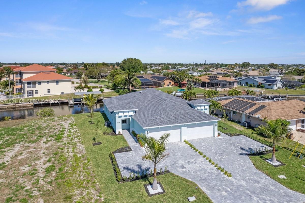 An aerial view shows a single-story house with a gray roof and paved driveway — 1107 SE 38 ST, Cape Coral FL 33904, CAPE CORAL, FL