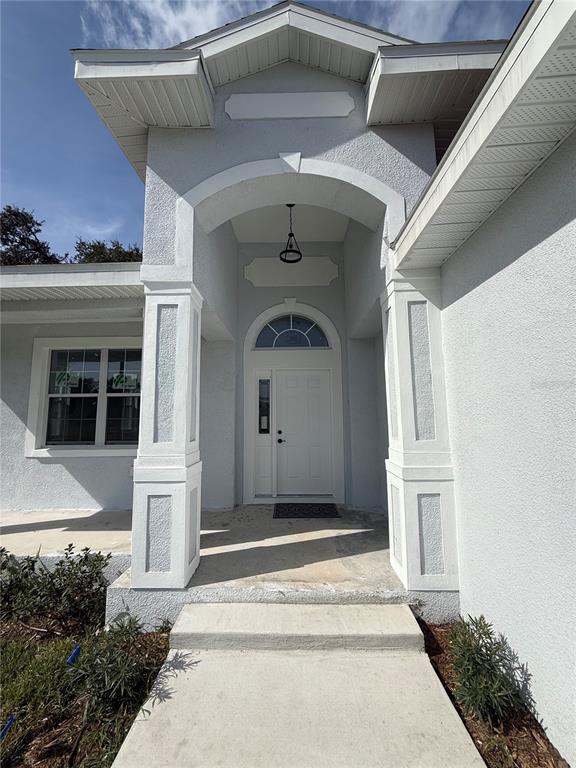 The exterior of a house features a white stucco facade, a covered entryway, and a door — 4205 57TH AVENUE N, ST PETERSBURG, FL
