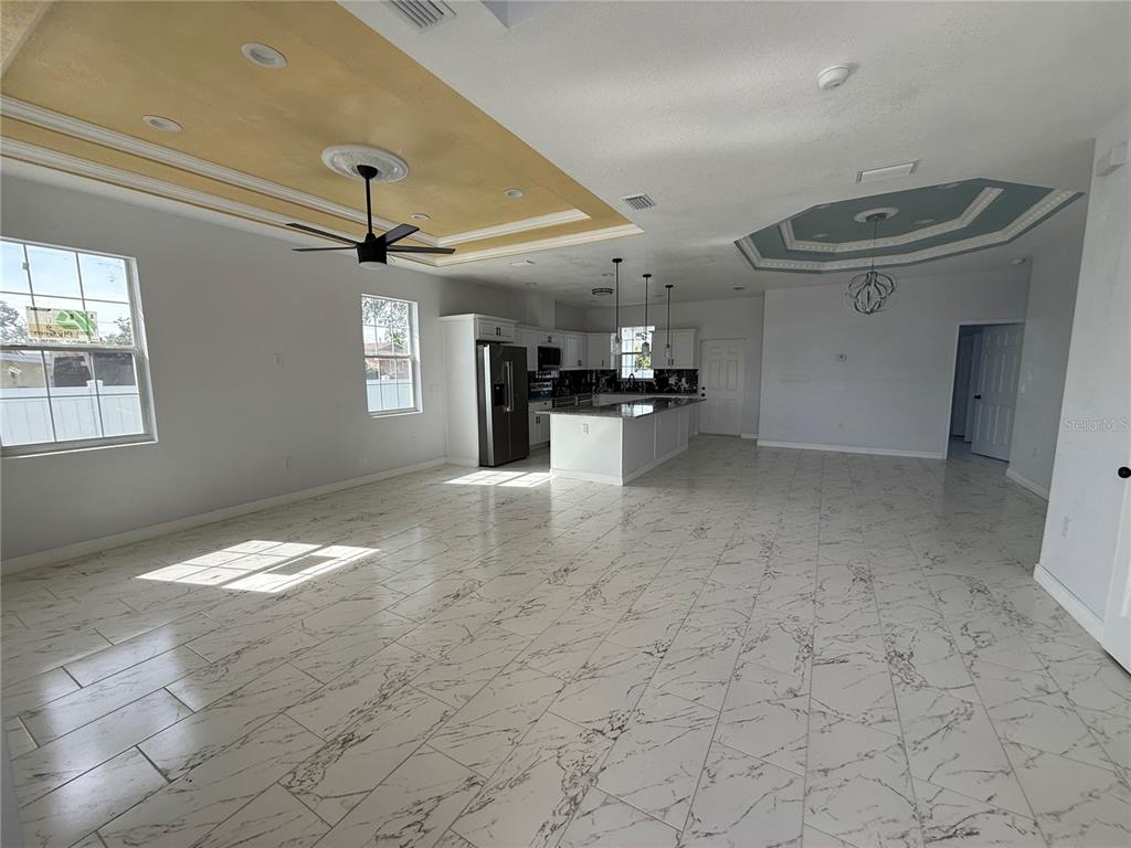 An open-concept kitchen and living area features white marble-look tile flooring and tray ceilings — 4205 57TH AVENUE N, ST PETERSBURG, FL