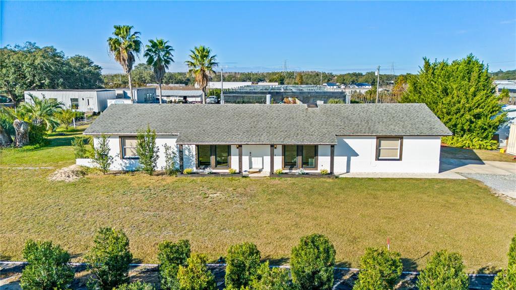 A single-story white house with a gray shingled roof sits on a large grassy lot — 4004 REX DRIVE, WINTER GARDEN, FL