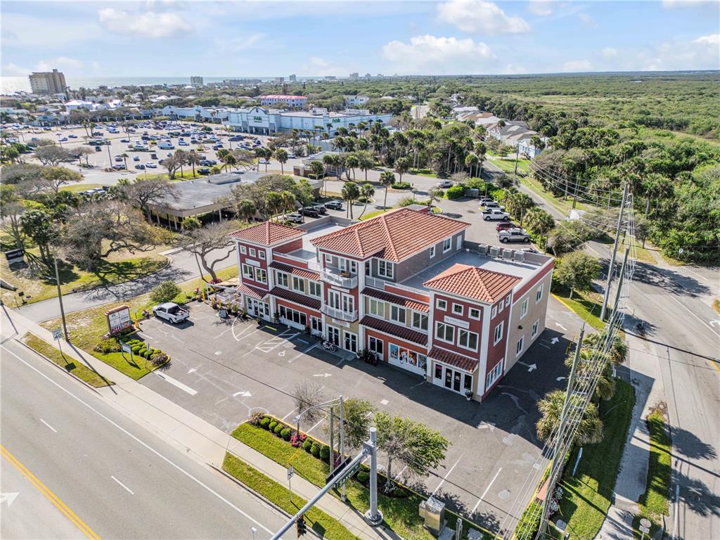 An aerial view of a multi-story commercial building with a tiled roof and parking lot — 701 E 3RD AVENUE UNIT 4, NEW SMYRNA BEACH, FL