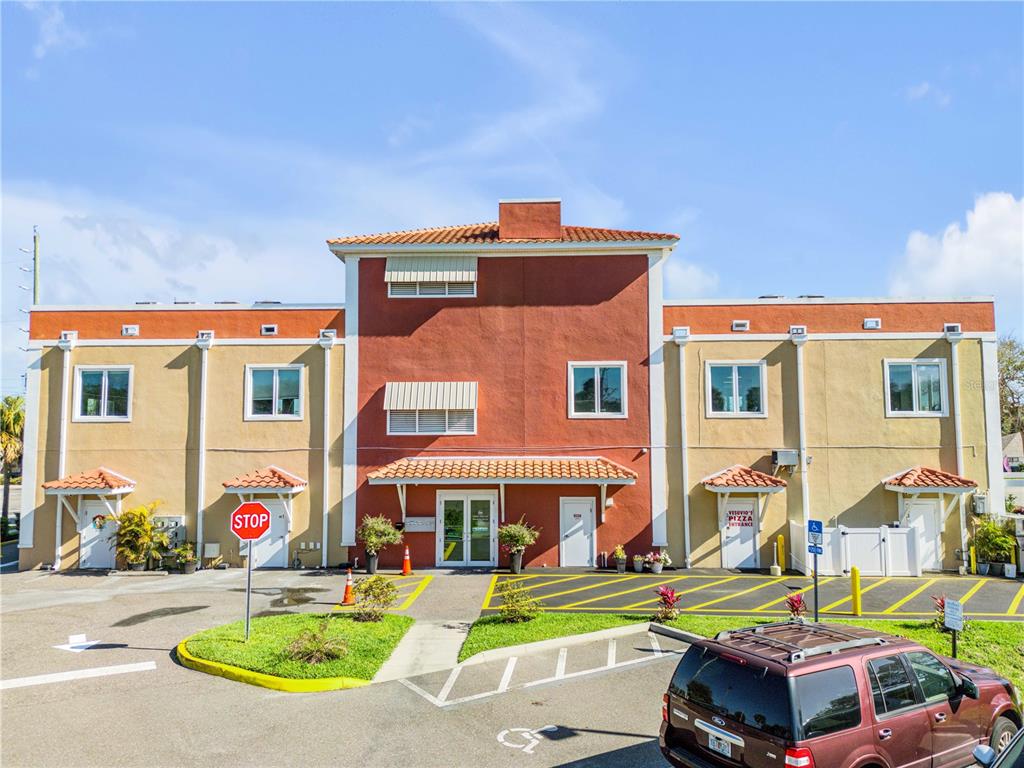 A two-story commercial building with a red center section, tan wings, and a parking lot — 701 E 3RD AVENUE UNIT 4, NEW SMYRNA BEACH, FL