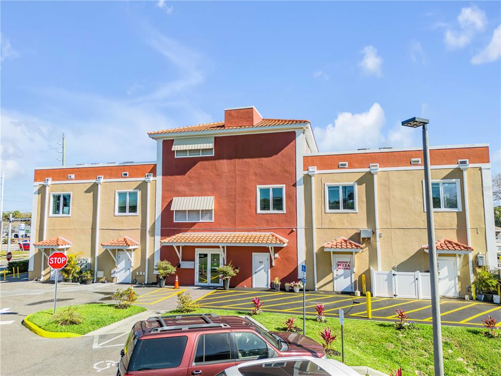 A two-story commercial building with a red and beige stucco exterior and parking lot — 701 E 3RD AVENUE UNIT 4, NEW SMYRNA BEACH, FL