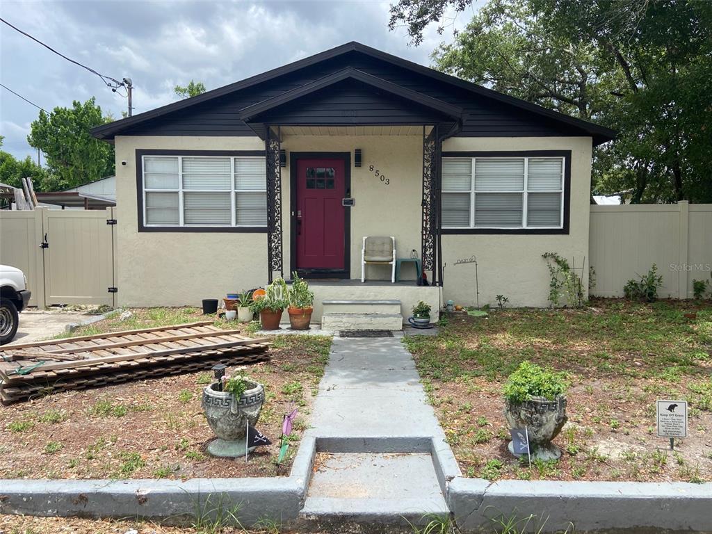 A single-story house with a beige stucco exterior, dark trim, and a red front door — 8503 N 11TH STREET, TAMPA, FL