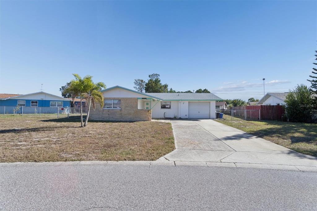 A single-story house with a stone facade, a concrete driveway, and a palm tree — 7608 REDCOAT AVENUE, PORT RICHEY, FL
