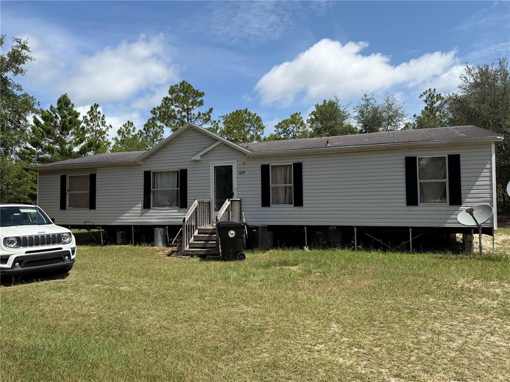 A single-story manufactured home with light siding stands on a grassy lot with a Jeep — 6274 EMORY AVENUE, KEYSTONE HEIGHTS, FL