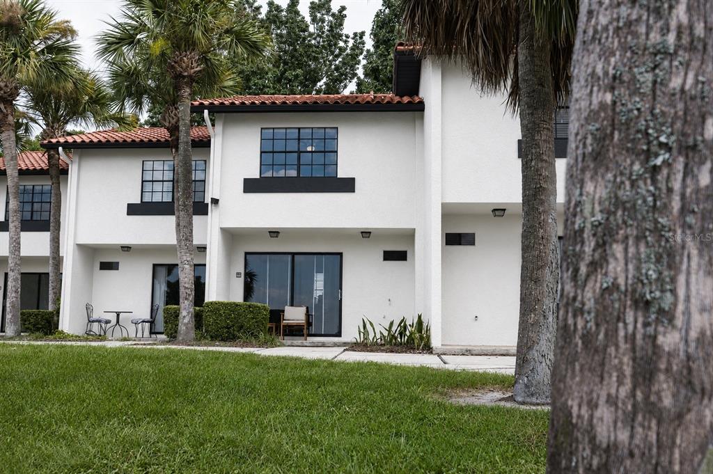 A two-story white stucco townhouse with a red tile roof and black window frames — 10330 TURKEY LAKE ROAD UNIT 109, ORLANDO, FL