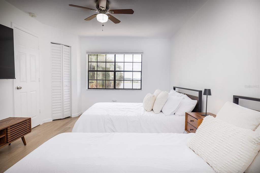 A bedroom features two beds, a ceiling fan, a window, and light wood-look flooring — 10330 TURKEY LAKE ROAD UNIT 109, ORLANDO, FL
