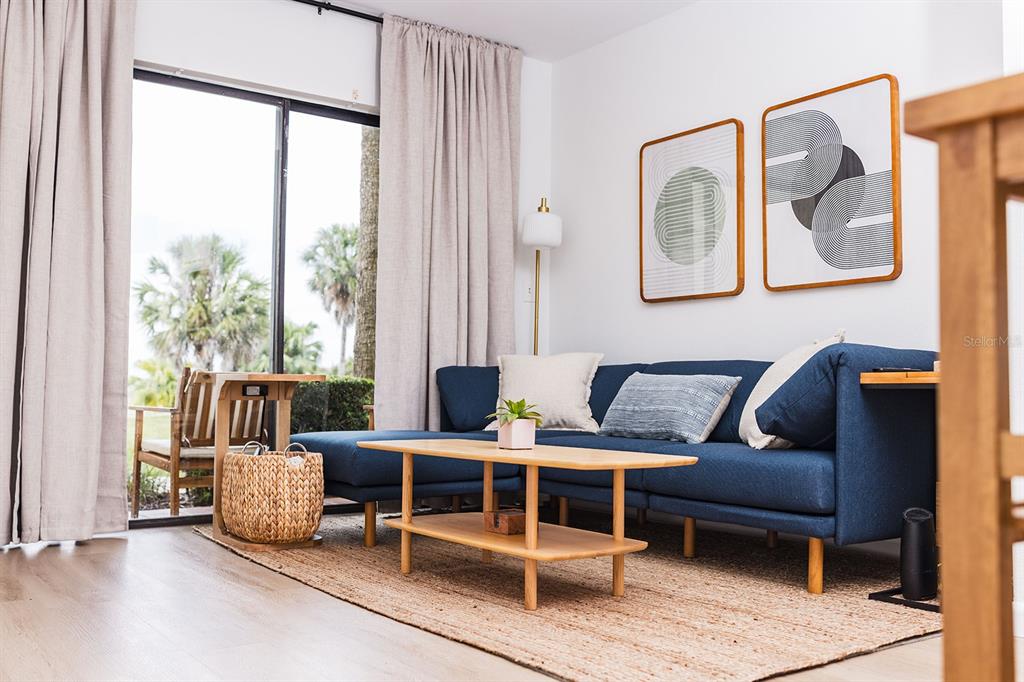 A living room features a blue sectional sofa, a wooden coffee table, and sliding glass doors — 10330 TURKEY LAKE ROAD UNIT 109, ORLANDO, FL