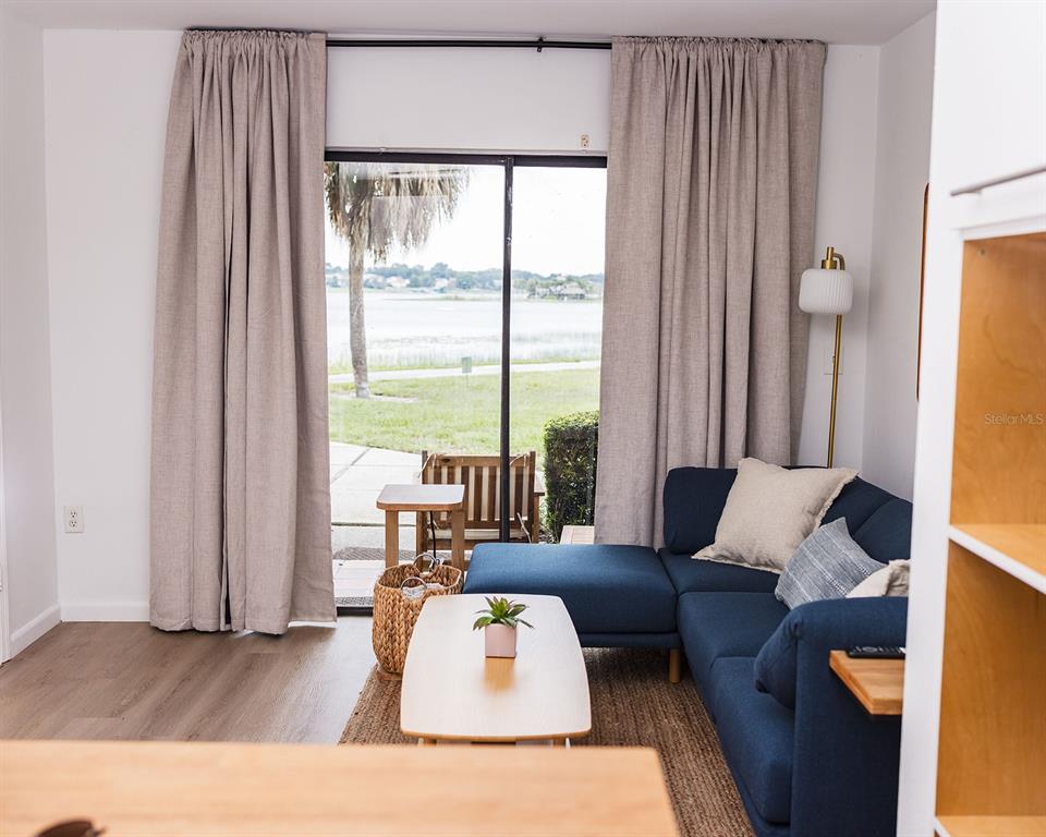 A living room features a blue sectional sofa, a coffee table, and sliding glass doors — 10330 TURKEY LAKE ROAD UNIT 109, ORLANDO, FL
