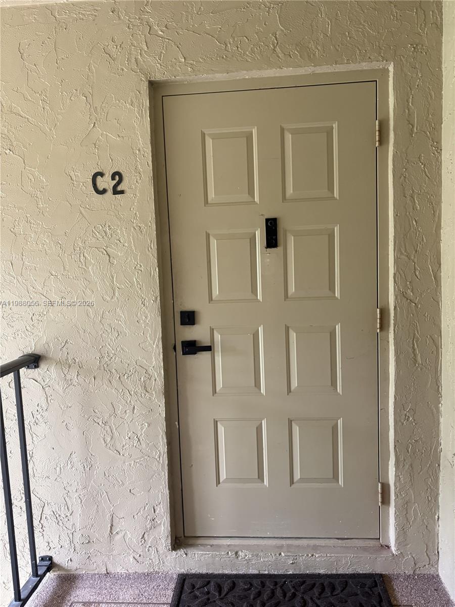 A beige exterior door labeled C2 is set into a textured stucco wall — 721 Sunny Pine Way # C2, Green Acres FL 33415, GREEN ACRES, FL