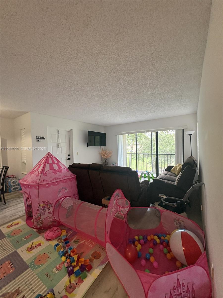 A living room features a brown sofa, a television, and a children's play tent set — 721 Sunny Pine Way # C2, Green Acres FL 33415, GREEN ACRES, FL
