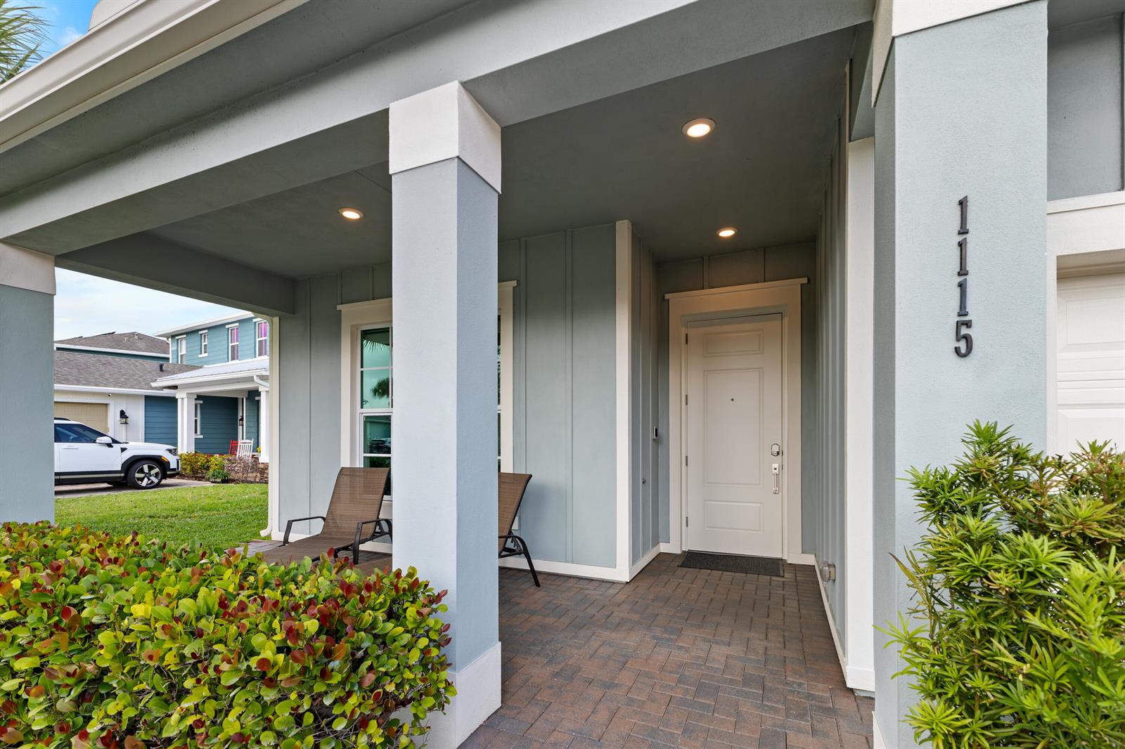A covered front porch features a white door, brick pavers, and two lounge chairs — 1115 Timber Reap Trail, FL 33470, FL
