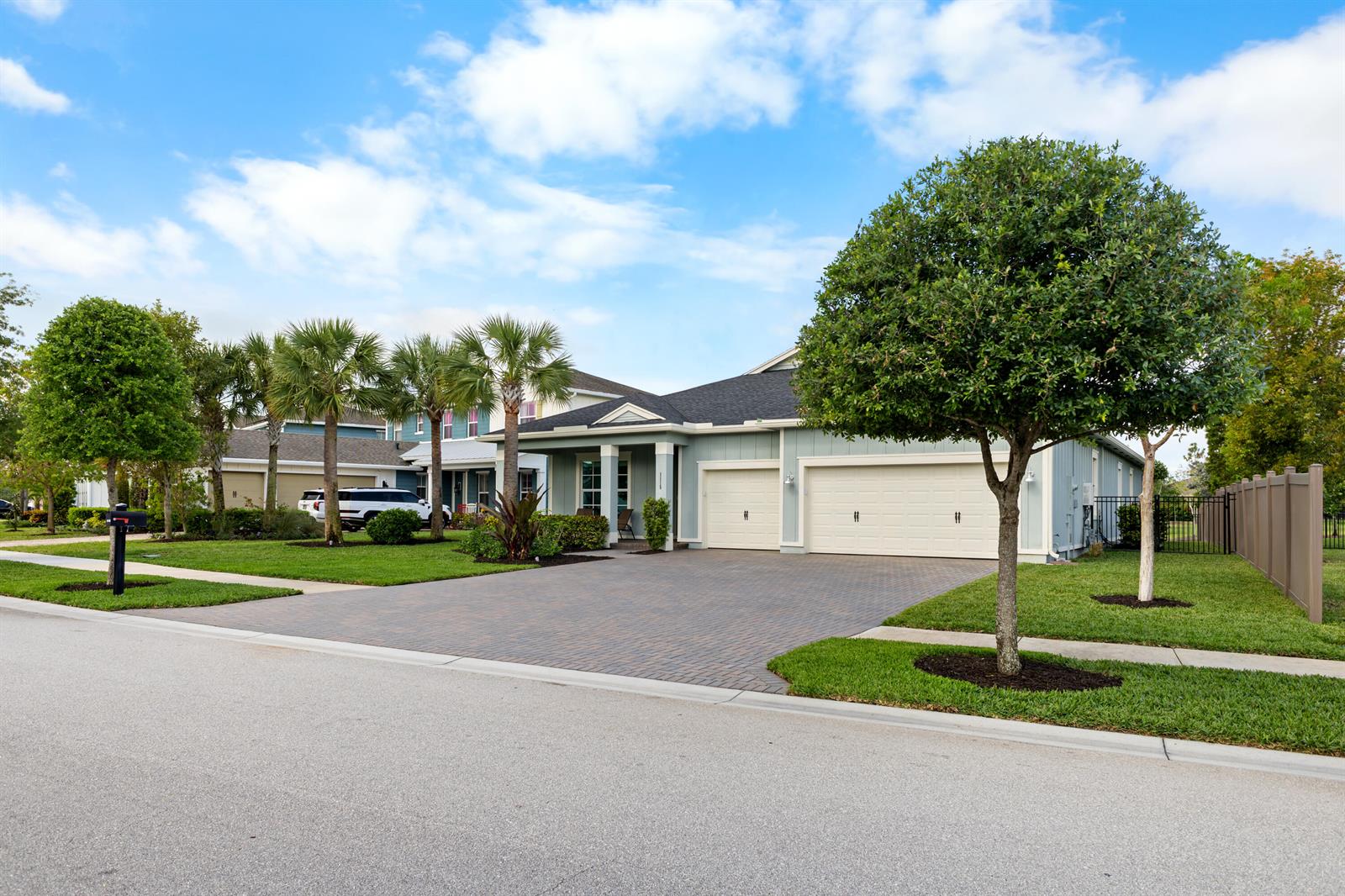 A light blue house with a three-car garage and a paved driveway sits on a lawn — 1115 Timber Reap Trail, FL 33470, FL