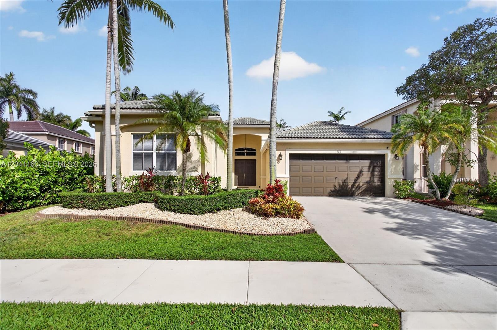 A single-story suburban house with a brown garage door, palm trees, and landscaped front yard — 786 Nandina Dr, Weston FL 33327, WESTON, FL