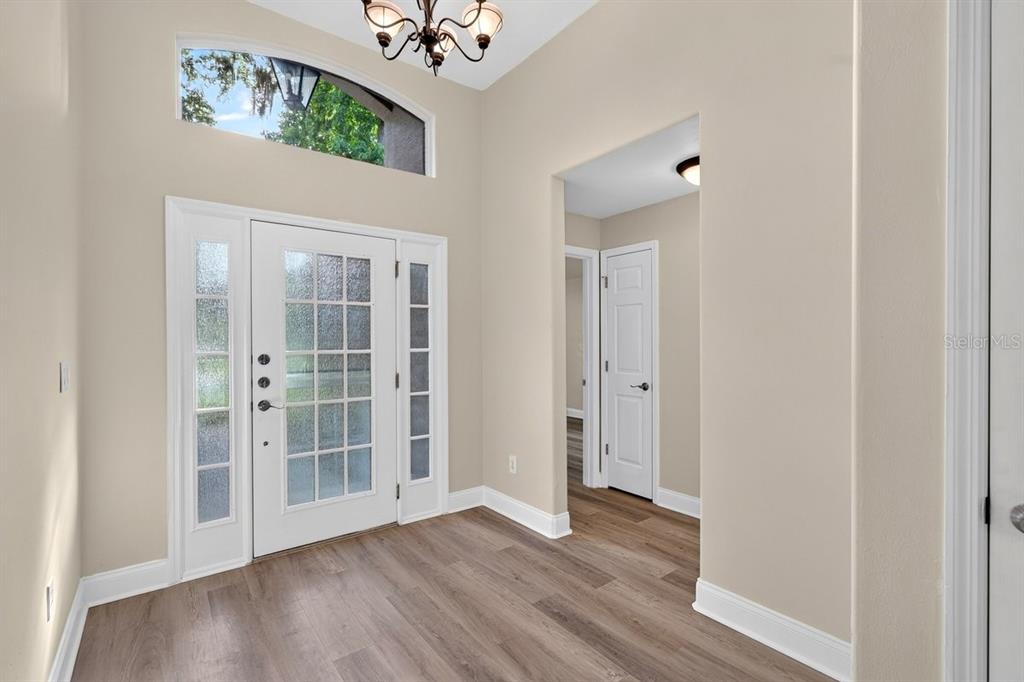 An entryway with light-colored walls, wood-look flooring, a white front door, and a transom window — 31 WILD CAT LANE, ORMOND BEACH, FL