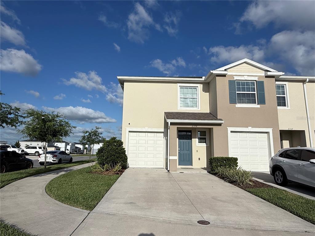 A two-story townhouse with a beige exterior, a single-car garage, and a concrete driveway — 2354 TAY WES DRIVE, ST CLOUD, FL