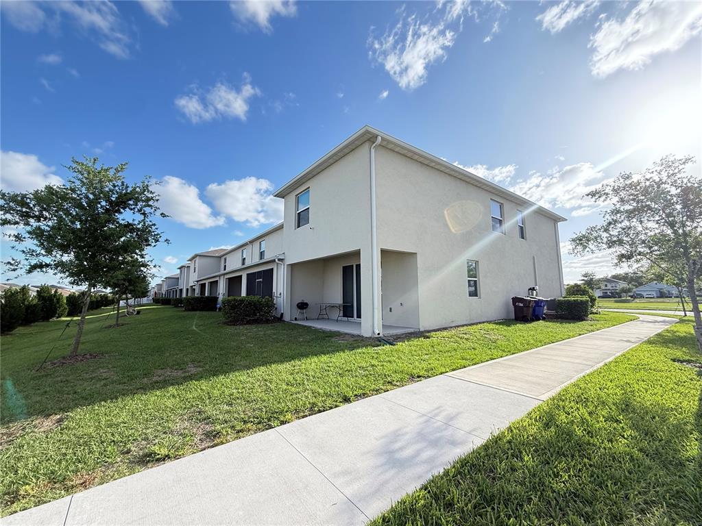 A side view of a multi-unit townhouse with a concrete patio and a sidewalk — 2354 TAY WES DRIVE, ST CLOUD, FL